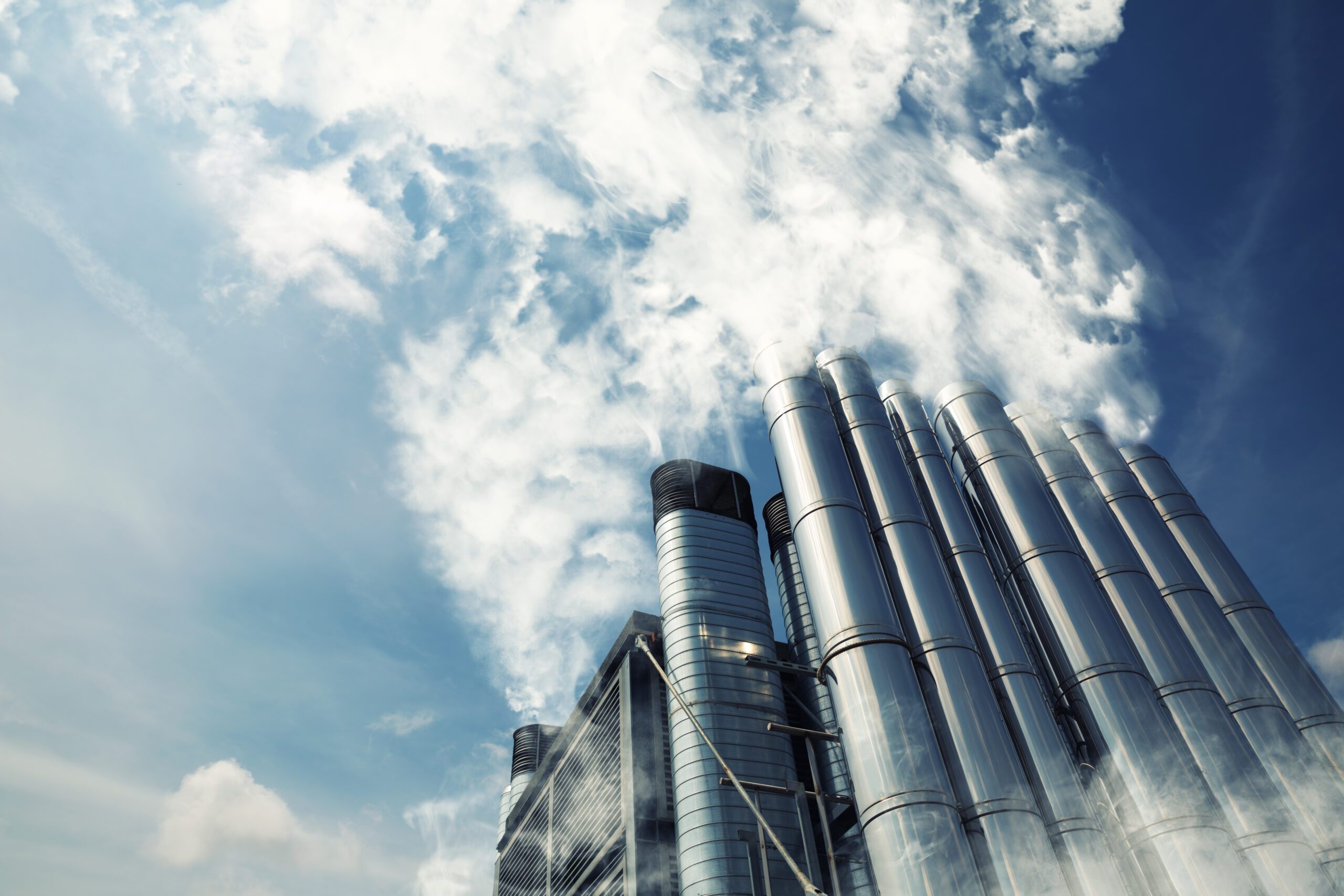 Smoking metal chimneys against blue sky